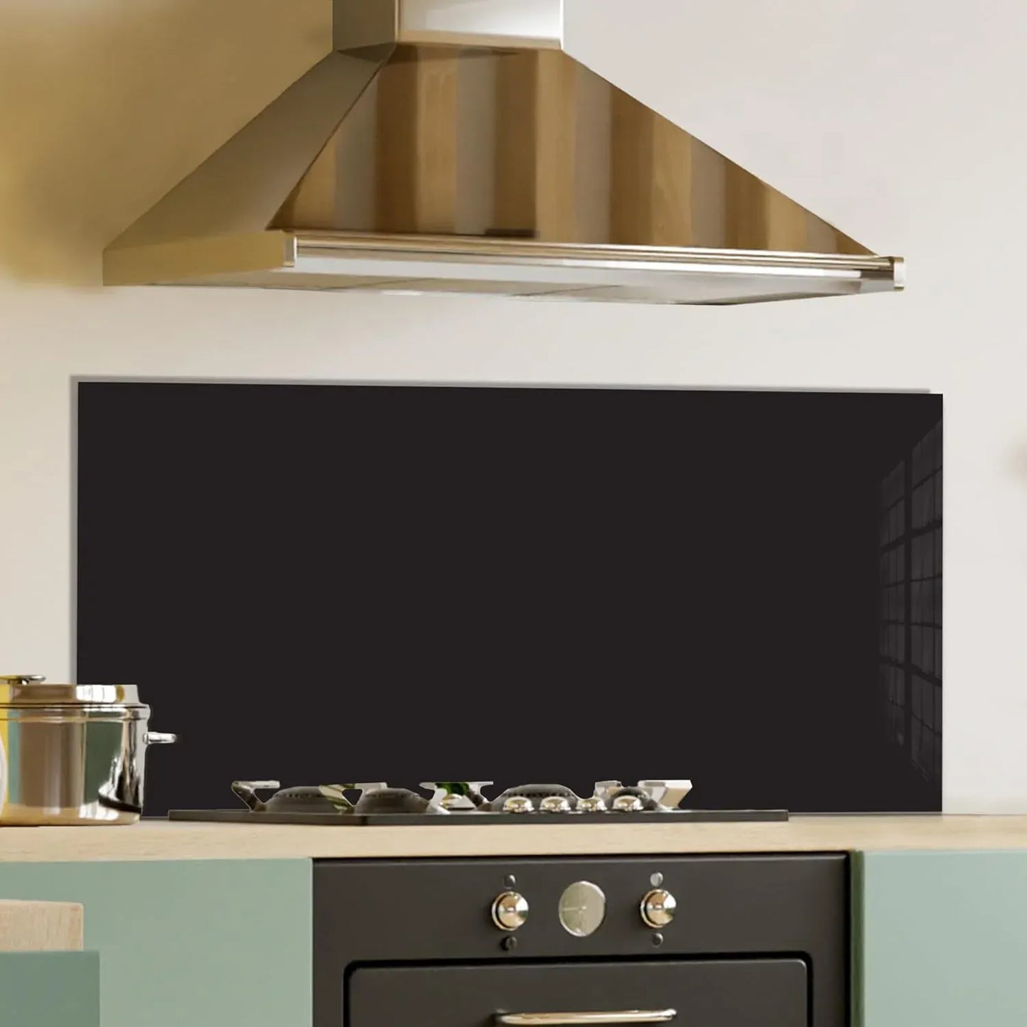 Black tempered glass kitchen backsplash behind stove with stainless steel range hood